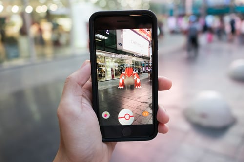 iPhone 7 held in one hand showing its screen with Pokemon Go Application